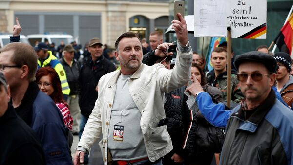 Lutz Bachmann (C), co-founder of the Pegida movement (Patriotic Europeans Against the Islamisation of the Occident), documents with his mobile phone as he takes part in a protest against German Chancellor Angela Merkel and her policy, on October 3, 2016, the German Unity Day, in Dresden, eastern Germany - Sputnik International