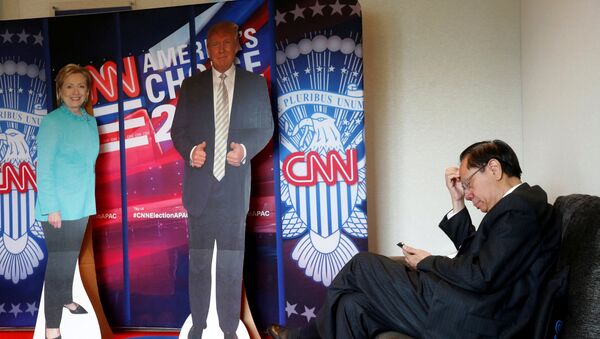 A man checks his smartphone beside cardboard cutouts of U.S. presidential candidates Hillary Clinton (L) and Donald Trump, at an event held by the American Chamber of Commerce in Hong Kong, China November 9, 2016. - Sputnik International