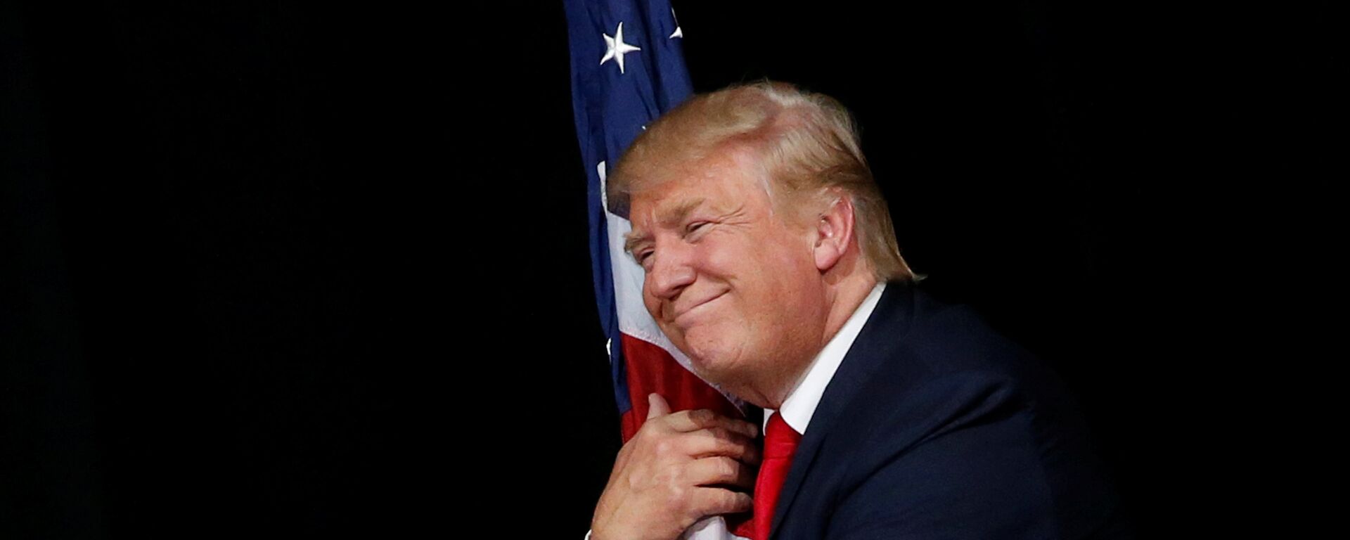   Donald Trump hugs a U.S. flag as he comes onstage to rally with supporters in Tampa, Florida, U.S. October 24, 2016 - Sputnik International, 1920, 12.09.2021