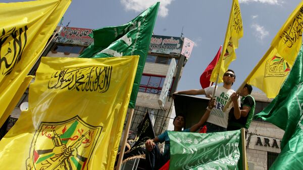 Palestinian supporters of Hamas Islamist movement and of Fatah party wave their faction's flags during a rally to support the Palestinian political unity deal, in the West Bank city of Jenin. (File) - Sputnik International