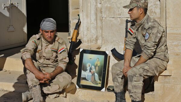 Iraqi Christian soldiers from the Nineveh Plain Protection Unit, sit next to a poster showing the Virgin Mary and Jesus Christ outside St. Addai church which was damaged by Islamic State fighters during their occupation of Keramlis village, less than 18 miles, 29 kilometers, southeast of Mosul, Iraq, Sunday Nov. 13, 2016 - Sputnik International