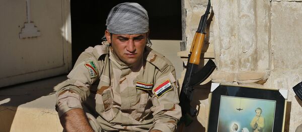 Iraqi Christian soldiers from the Nineveh Plain Protection Unit, sit next to a poster showing the Virgin Mary and Jesus Christ outside St. Addai church which was damaged by Islamic State fighters during their occupation of Keramlis village, less than 18 miles, 29 kilometers, southeast of Mosul, Iraq, Sunday Nov. 13, 2016 Iraqi Christian soldiers from the Nineveh Plain Protection Unit, sit next to a poster showing the Virgin Mary and Jesus Christ outside St. Addai church which was damaged by Islamic State fighters during their occupation of Keramlis village, less than 18 miles, 29 kilometers, southeast of Mosul, Iraq, Sunday Nov. 13, 2016 - Sputnik International