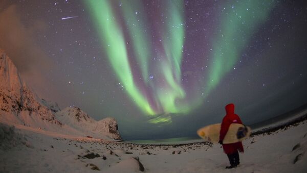 A surfer looks at northern lights ( aurora borealis ) at the snow covered beach of Unstad, on Lofoten Island, Arctic Circle, on March 9, 2016 - Sputnik International