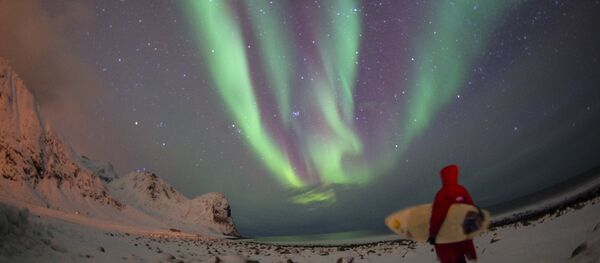 A surfer looks at northern lights ( aurora borealis ) at the snow covered beach of Unstad, on Lofoten Island, Arctic Circle, on March 9, 2016 A surfer looks at northern lights ( aurora borealis ) at the snow covered beach of Unstad, on Lofoten Island, Arctic Circle, on March 9, 2016 - Sputnik International