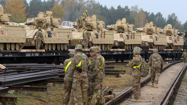 Members of the US Army 1st Brigade, 1st Cavalry Division, unload heavy combat equipment including Bradley Fighting Vehicles at the railway station near the Rukla military base in Lithuania, on October 4, 2014 - Sputnik International
