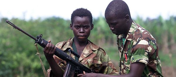 A fourteen year old child soldier for the Sierra Leone Army, Abu Kamara, left, is helped with his British self Loading rifle (SLR) by another soldier while protecting the small town of Ropath near Masiaka, 55 km east of the capital Freetown, Tuesday May 23, 2000 - Sputnik International
