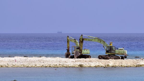 Two excavators are pictured at a construction site on Taiping island in the Spratly chain in the South China Sea on March 23, 2016 - Sputnik International