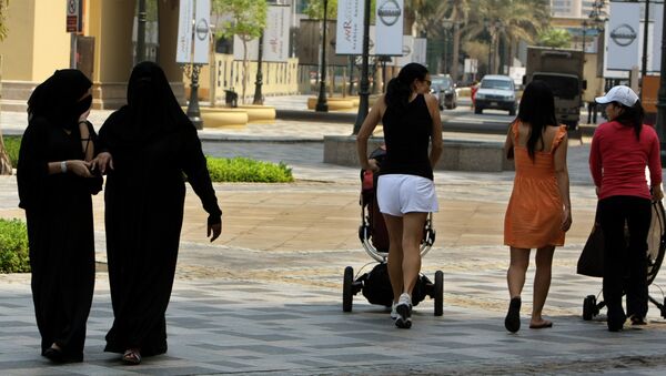 Foreign women walk past fully-veiled local women in the Gulf emirate of Dubai on September 15, 2010. - Sputnik International