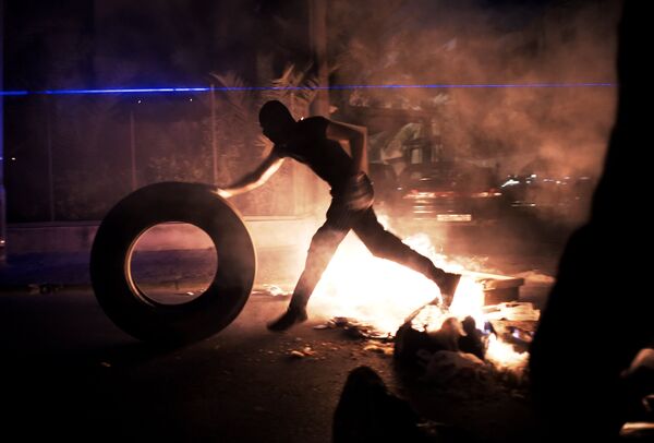 A Bahraini protester puts tyre in fire during clashes between protesters and riot police following a protest to demand more rights and against the ruling regime, late on July 10, 2014 in the village of Sanabis, west of Manama. A Bahraini protester puts tyre in fire during clashes between protesters and riot police following a protest to demand more rights and against the ruling regime, late on July 10, 2014 in the village of Sanabis, west of Manama. - Sputnik International