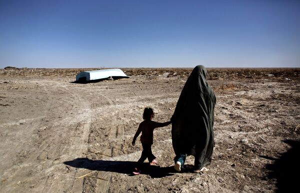 An Iranian woman walks with her daughter past an abandoned boat in Sikh Sar village at Hamoon wetland near the Zabol town, in southeastern province of Sistan-Baluchistan bordering Afghanistan on February 2, 2015. An Iranian woman walks with her daughter past an abandoned boat in Sikh Sar village at Hamoon wetland near the Zabol town, in southeastern province of Sistan-Baluchistan bordering Afghanistan on February 2, 2015. - Sputnik International