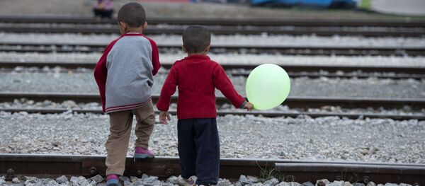 Children cross rail tracks at a makeshift camp for migrants and refugees near the village of Idomeni not far from the Greek-Macedonian border Children cross rail tracks at a makeshift camp for migrants and refugees near the village of Idomeni not far from the Greek-Macedonian border - Sputnik International