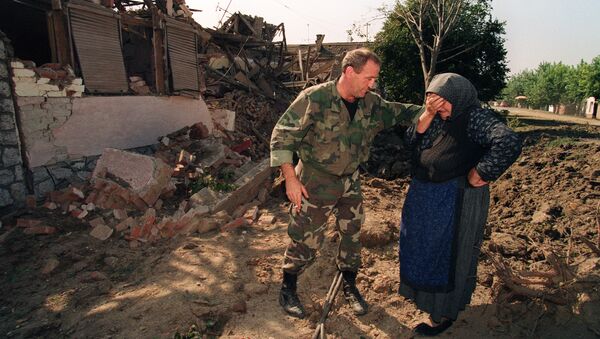 A Croatian National Guardsman comforts an old woman on September 26, 1991, outside her home which was destroyed in an air raid during the night by Yugoslav Serbian Federal air forces - Sputnik International