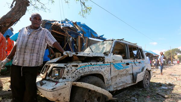 Somali rescuer stands near the wreckage of a car destroyed in an explosion at a police checkpoint next to a busy market in the Somali capital Mogadishu, November 26, 2016 - Sputnik International