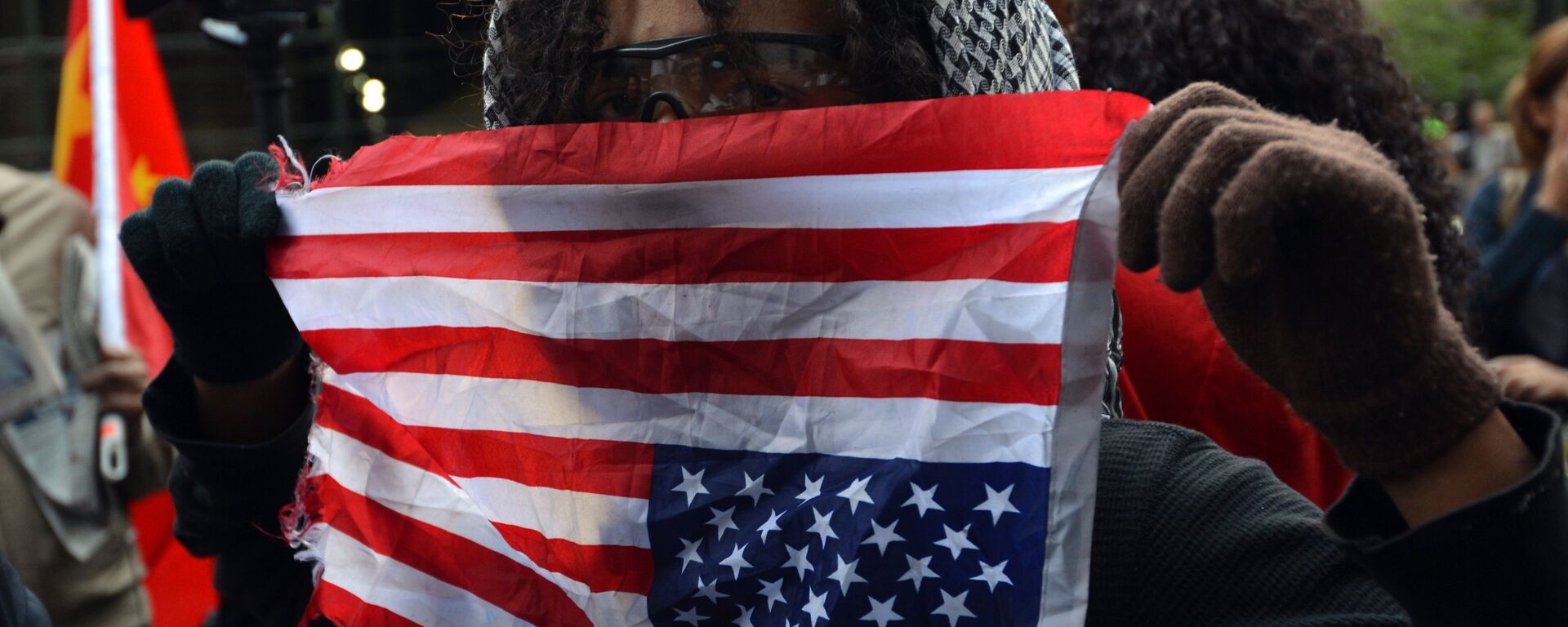 An Occupy Wall Street protester holds an American flag upside down as a sign of distress near Wall Street September 17, 2012 on the one year anniversary of the movement in New York - Sputnik International, 1920, 13.06.2022