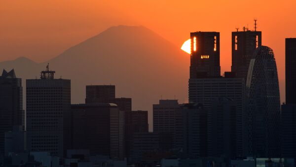 This picture taken on November 7, 2016 shows the sun setting behind the Japan's highest mountain Mount Fuji and skyscrapers in Tokyo's Shinjuku area. - Sputnik International