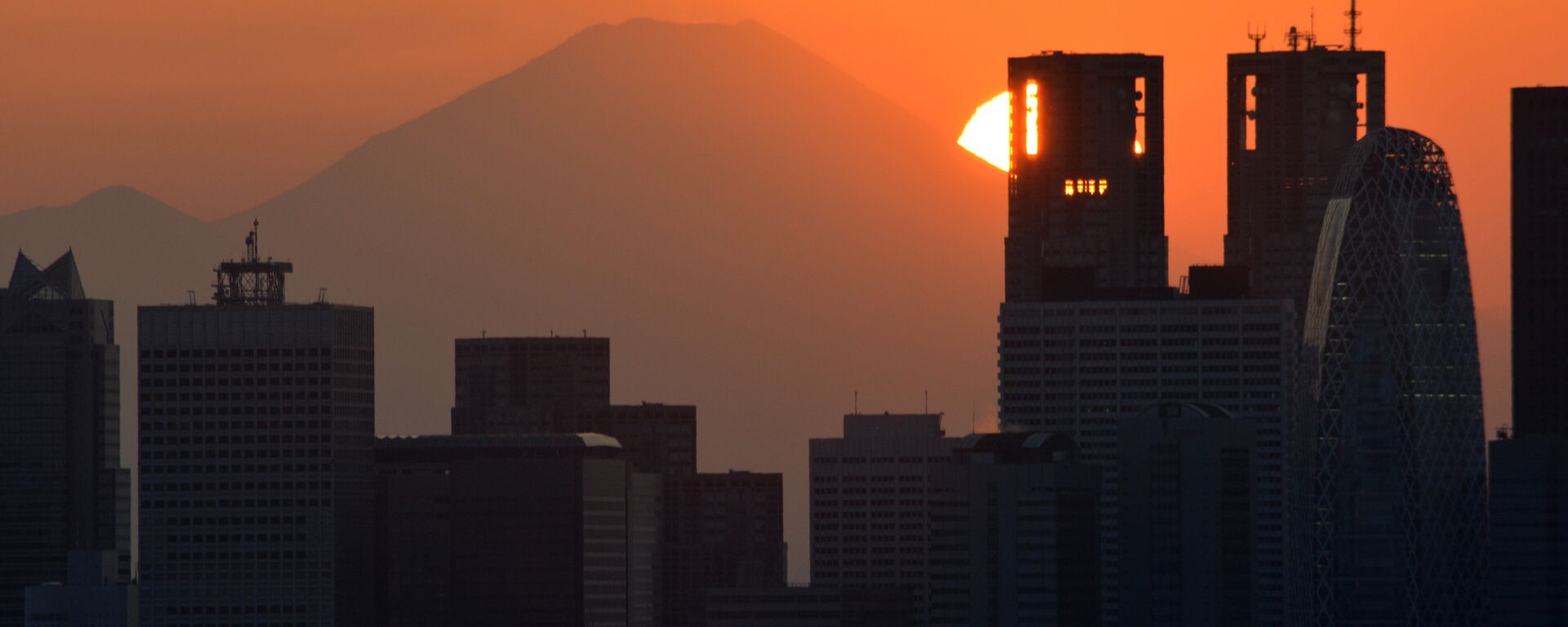 This picture taken on November 7, 2016 shows the sun setting behind the Japan's highest mountain Mount Fuji and skyscrapers in Tokyo's Shinjuku area. - Sputnik International, 1920, 23.12.2018