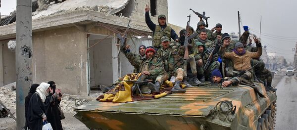 Syrian pro-government forces sit on a military vehicle driving past residents fleeing the eastern part of Aleppo and gathering in Masaken Hanano, a former rebel-held district which was retaken by the regime forces last week, on November 30, 2016. Syrian pro-government forces sit on a military vehicle driving past residents fleeing the eastern part of Aleppo and gathering in Masaken Hanano, a former rebel-held district which was retaken by the regime forces last week, on November 30, 2016. - Sputnik International
