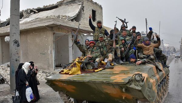 Syrian pro-government forces sit on a military vehicle driving past residents fleeing the eastern part of Aleppo and gathering in Masaken Hanano, a former rebel-held district which was retaken by the regime forces last week, on November 30, 2016. - Sputnik International