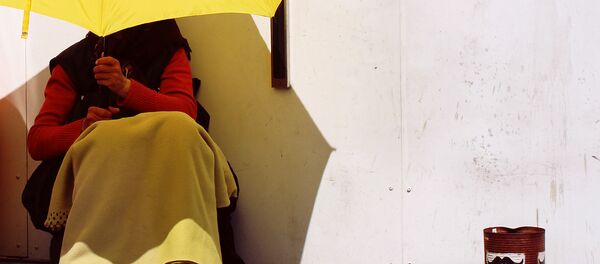 A beggar shields herself from the sun using a bright yellow umbrella, Malmo, Sweden - Sputnik International