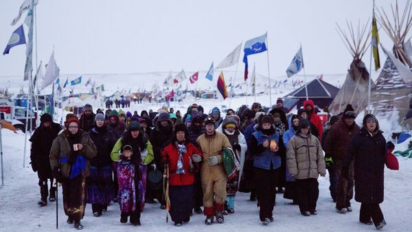 In this Thursday, Dec. 1, 2016 photo, Beatrice Menase Kwe Jackson, center, walks with Daniel Emory, both of the Ojibwe Native American tribe as they lead a procession to the Cannonball river for a traditional water ceremony at the Oceti Sakowin camp where people have gathered to protest the Dakota Access oil pipeline in Cannon Ball, N.D. - Sputnik International