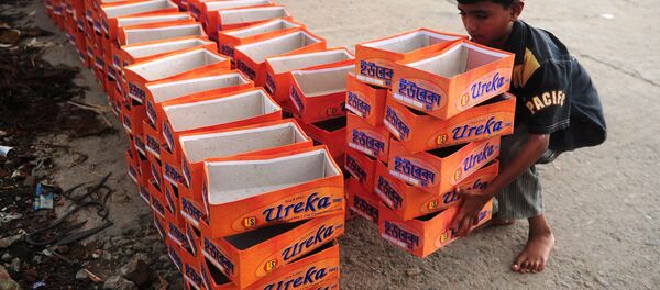 A Bangladeshi child lifts shoe boxes at a factory in Dhaka on August 7, 2012. - Sputnik International
