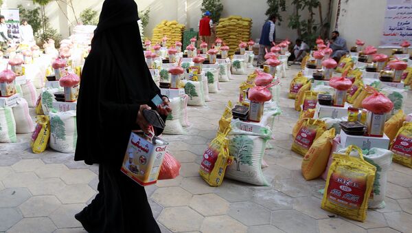 A Yemeni woman affected by the country's ongoing conflict walks past food rations provided by an initiative organised by a local charity in the capital Sanaa on June 2, 2016. - Sputnik International
