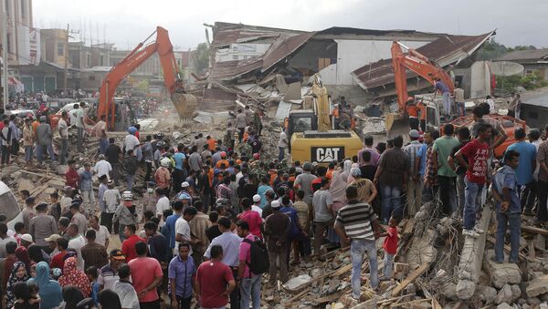 Rescuers use excavators to search for victims under the rubble of collapsed buildings after an earthquake in Pidie Jaya, Aceh province, Indonesia - Sputnik International