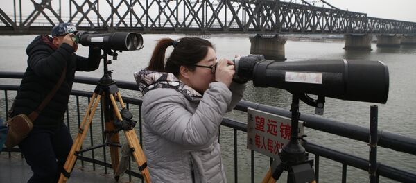 Chinese tourists watch the North Korean side across the Yalu River using telescopes in Dandong, Northeast China's Liaoning Province - Sputnik International