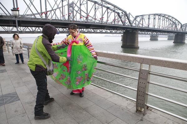 A tourist in traditional Korean costume poses for photos beside the river. - Sputnik International