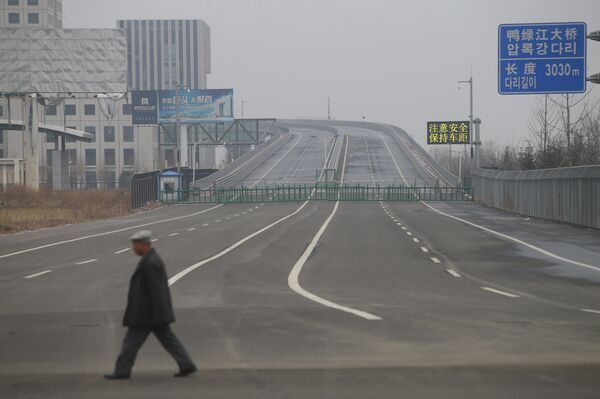A man walks past the new Yalu Bridge in Dandong. The Chinese side of the bridge is finished, but construction on the Korean side has been halted due to a shortage of funds.  - Sputnik International