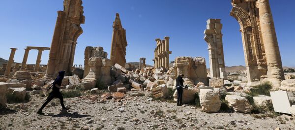 Journalists walk near the remains of the Monumental Arch in the historical city of Palmyra, in Homs Governorate, Syria April 1, 2016 - Sputnik International