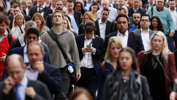 A commuter looks at his mobile phone as he crosses London Bridge during rush hour in. - Sputnik International