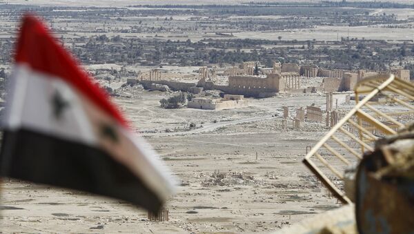 A Syrian national flag flutters as the ruins of the historic city of Palmyra are seen in the background, in Homs Governorate, Syria April 1, 2016. - Sputnik International