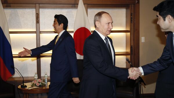 Russian President Vladimir Putin, center, shakes hands with a Japanese official as Japanese Prime Minister Shinzo Abe, left, prepares to greet a member of the Russian delegation during their meeting in Nagato, Japan, Thursday, Dec. 15, 2016. - Sputnik International
