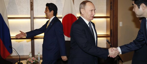 Russian President Vladimir Putin, center, shakes hands with a Japanese official as Japanese Prime Minister Shinzo Abe, left, prepares to greet a member of the Russian delegation during their meeting in Nagato, Japan, Thursday, Dec. 15, 2016. - Sputnik International