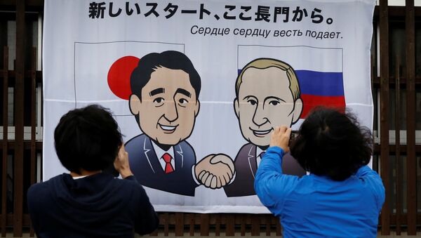 People take photos of a banner showing Japan's Prime Minister Shinzo Abe and Russian President Vladimir Putin at the Senzaki station in Nagato, Yamaguchi prefecture, Japan, December 14, 2016, a day before their summit meeting. The words on top reads, A new start from here in Nagato. - Sputnik International
