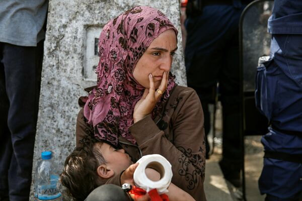 A woman sits with her child after migrants and refugees tried to open the border fence at a makeshift camp at the Greek-Macedonian border near the village of Idomeni, Greece, April 7, 2016. A woman sits with her child after migrants and refugees tried to open the border fence at a makeshift camp at the Greek-Macedonian border near the village of Idomeni, Greece, April 7, 2016. - Sputnik International
