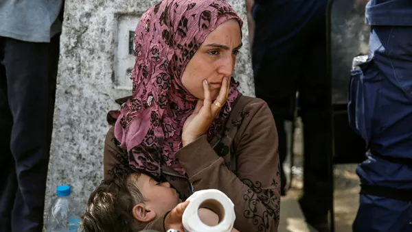 A woman sits with her child after migrants and refugees tried to open the border fence at a makeshift camp at the Greek-Macedonian border near the village of Idomeni, Greece, April 7, 2016. - Sputnik International