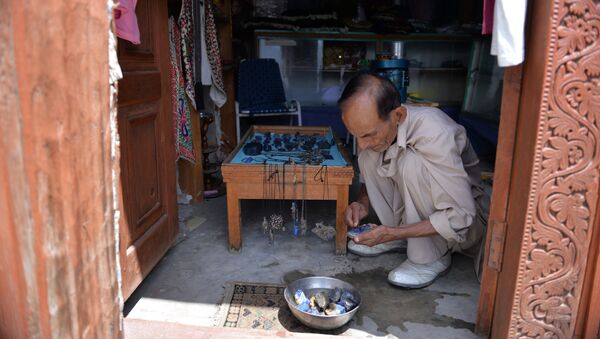 A shopkeeper polishes gemstones at his shop in Karimabad town of northern Hunza valley - Sputnik International