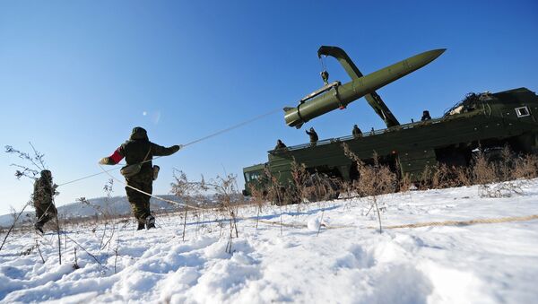 Russian soldiers watch a transporter-loader place an Iskander-M shorter-range missile onto a launcher during an exercise - Sputnik International