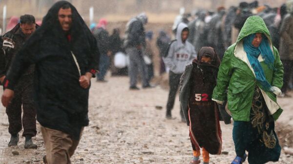 Displaced Iraqis, who fled the Islamic State stronghold of Mosul, walk under rain in Khazer camp, Iraq December 14, 2016 - Sputnik International