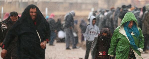 Displaced Iraqis, who fled the Islamic State stronghold of Mosul, walk under rain in Khazer camp, Iraq December 14, 2016 - Sputnik International