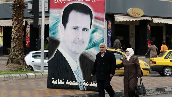 Syrians walk past a portrait of President Bashar al-Assad in the capital Damascus on March 15, 2016 - Sputnik International