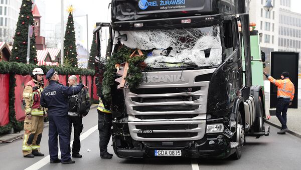 A policeman and firemen stand next to a truck on December 20, 2016 at the scene where it crashed into a Christmas market near the Kaiser-Wilhelm-Gedaechtniskirche (Kaiser Wilhelm Memorial Church) in Berlin - Sputnik International