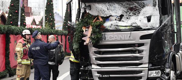 A policeman and firemen stand next to a truck on December 20, 2016 at the scene where it crashed into a Christmas market near the Kaiser-Wilhelm-Gedaechtniskirche (Kaiser Wilhelm Memorial Church) in Berlin - Sputnik International