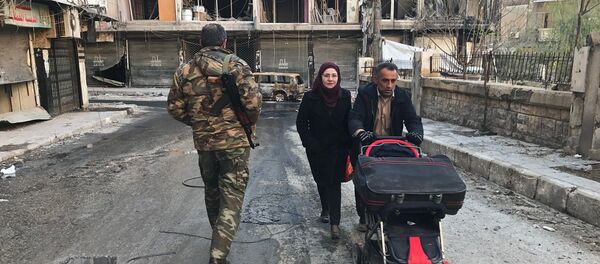 Local residents pass a soldier on a street in Aleppo. - Sputnik International
