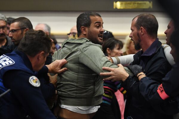 A protester is restrained by policemen after having interrupted the municipal council in Beziers, southern France, on October 18, 2016, as he demonstrates with other people against the local referendum on the welcoming of migrants to the city planned to take place at the end of the meeting - Sputnik International