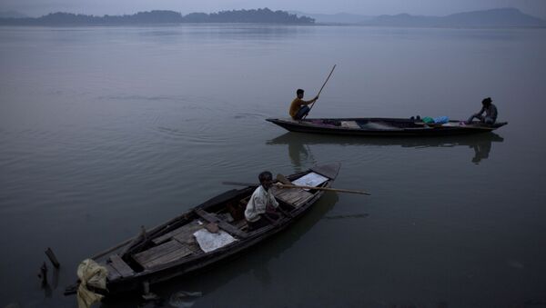 An Indian fisherman paddles a country boat as he leaves for fishing as another man sits in an anchored boat in the river Brahmaputra in Gauhati, India - Sputnik International