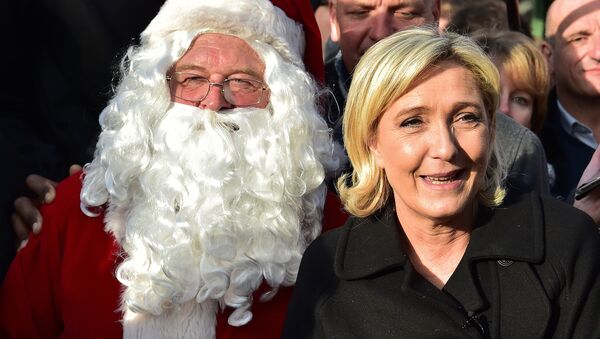 French far-right Front National (FN) party president, member of European Parliament and candidate for France's 2017 presidential election, Marine Le Pen smiles as she poses for pictures with Santa Claus during a visit of a Christmas market in Paris on December 8, 2016 - Sputnik International