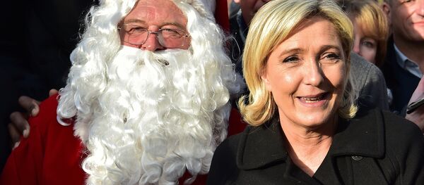 French far-right Front National (FN) party president, member of European Parliament and candidate for France's 2017 presidential election, Marine Le Pen smiles as she poses for pictures with Santa Claus during a visit of a Christmas market in Paris on December 8, 2016 - Sputnik International